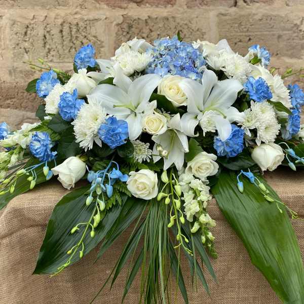 White lilies and roses with blue flowers in a low arrangement