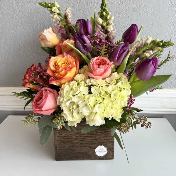 Mixed bouquet of roses, tulips, and hydrangeas in a wooden box