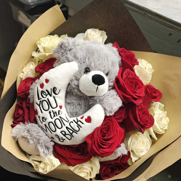 Bouquet of red and white roses with a gray teddy bear holding a moon pillow