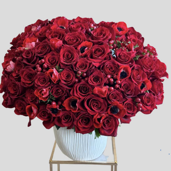 Large bouquet of red roses and red anemones in a white vase