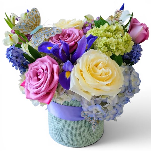 Mixed bouquet of roses, hydrangeas, and irises in a wrapped hatbox