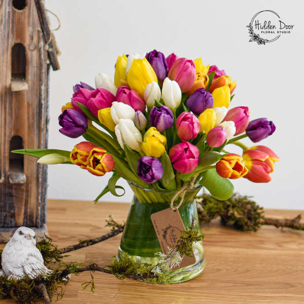 Colorful tulips arranged in a glass vase with moss accents
