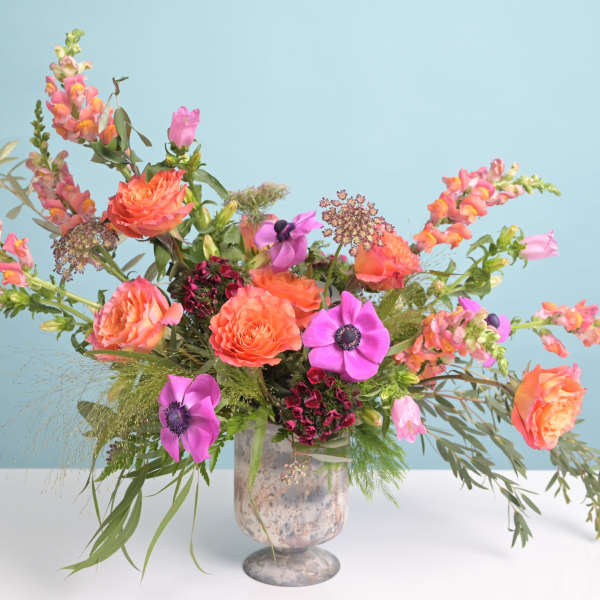 Bright mixed bouquet in a glass vase with orange and pink blooms