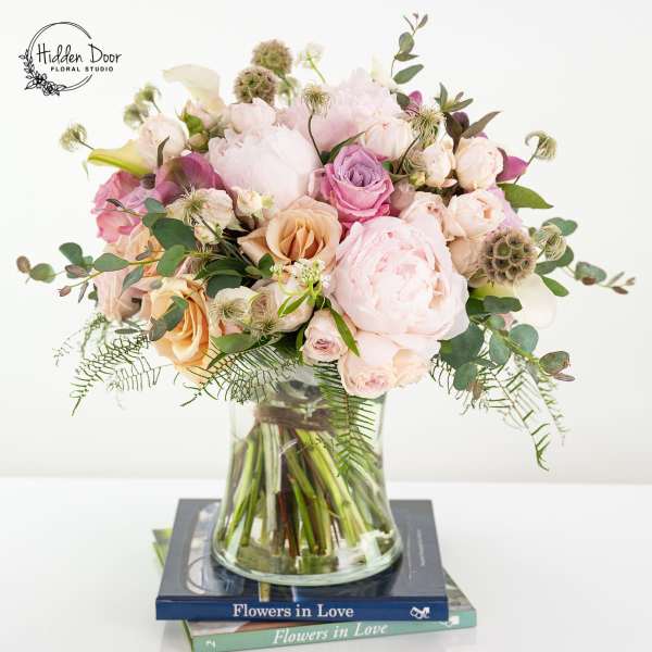 Pastel bouquet of roses and peonies in a clear glass vase