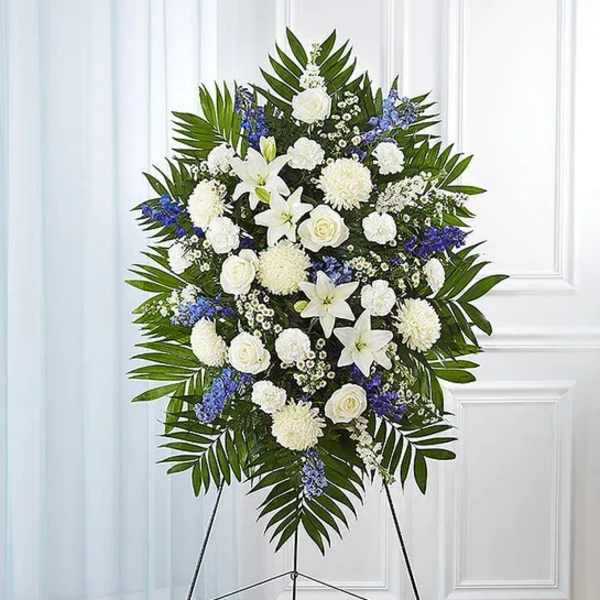 Standing funeral spray with white lilies, roses, and blue flowers
