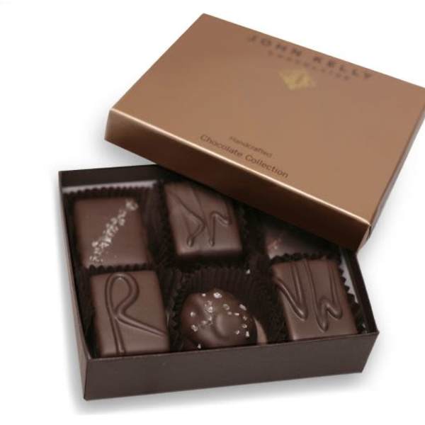 Open brown box of assorted dark chocolates with decorative toppings