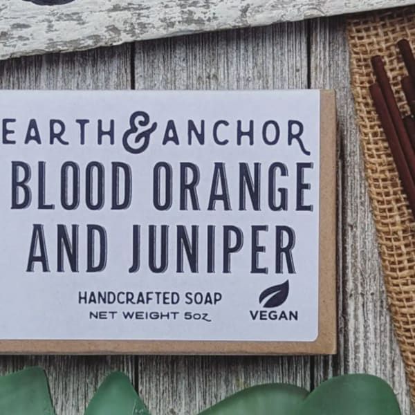 Box of blood orange and juniper handcrafted vegan soap on a rustic wood surface