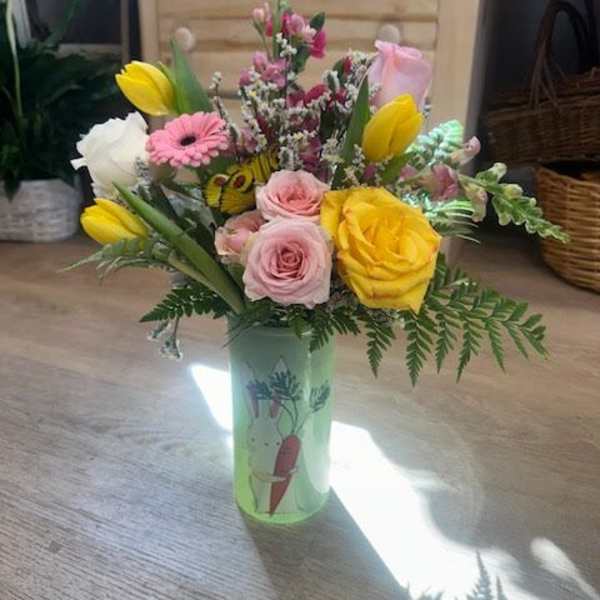 Mixed bouquet of roses, tulips, and a pink gerbera in a decorated vase