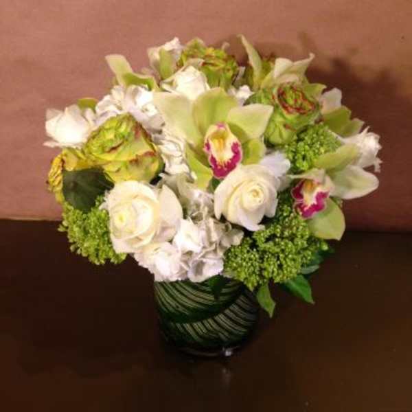 White and green floral arrangement in a striped glass vase