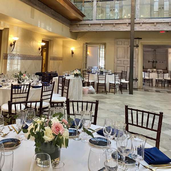 Floral centerpieces on round banquet tables in a decorated reception hall