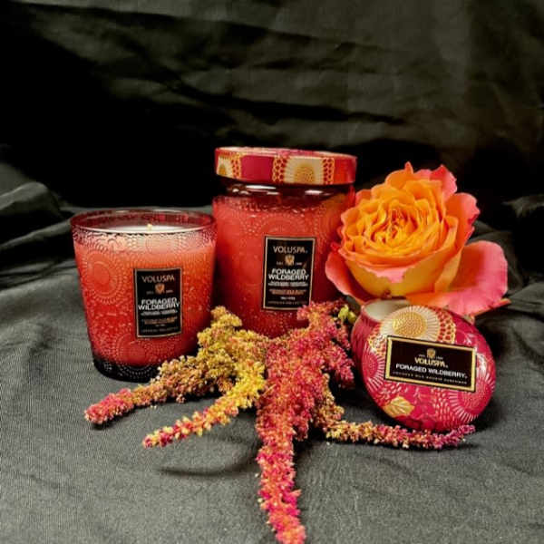 Two red candles with a rose and dried floral sprigs