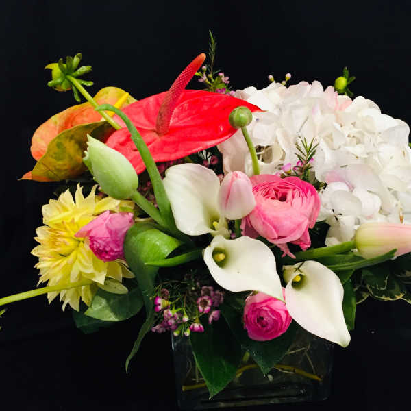 Mixed bouquet with white hydrangea, pink anthurium, and calla lilies in a glass vase