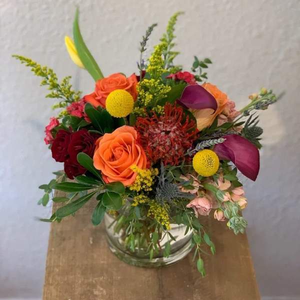 Mixed bouquet in a clear glass vase with orange and purple blooms