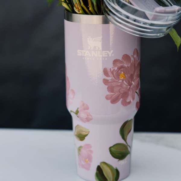 Pink floral Stanley tumbler holding green stems and leaves