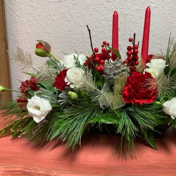 Low holiday centerpiece with red and white flowers and two red candles
