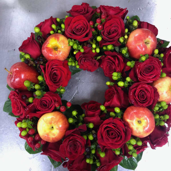 Heart-shaped arrangement of red roses with apples and berry accents