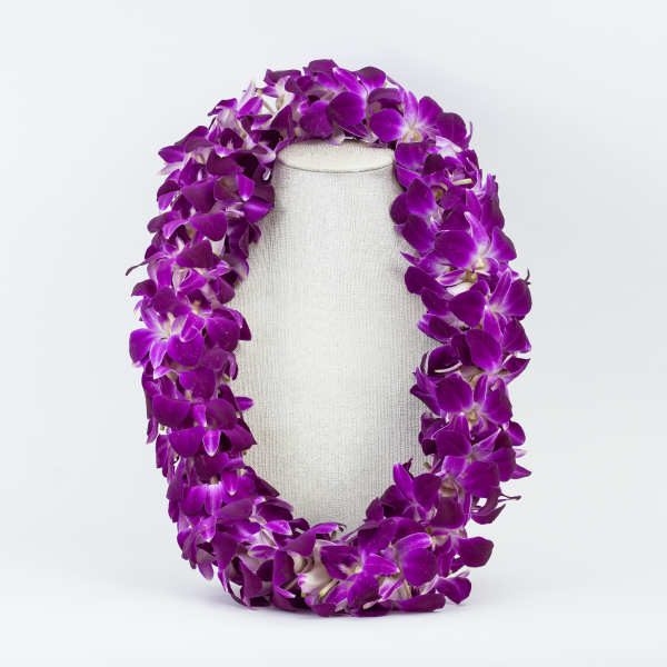 Purple orchid lei draped over a light fabric display form
