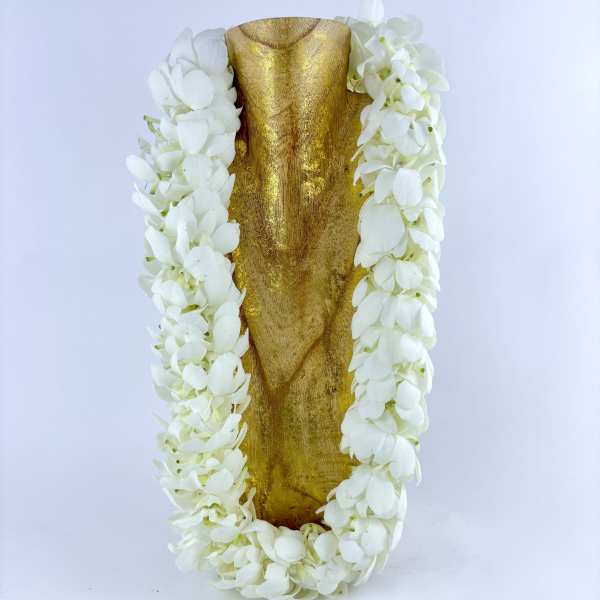 White flower lei draped over a gold decorative object