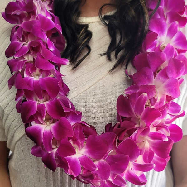 Woman wearing a purple orchid lei over a light sweater