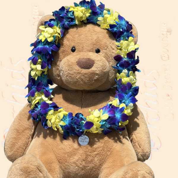 Teddy bear wearing a blue, purple, and yellow flower lei