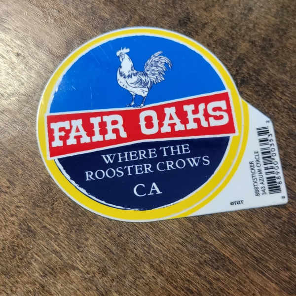 Fair Oaks sticker with a rooster logo on a wood surface