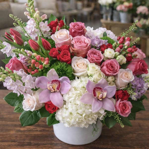 Mixed pink, red, and white floral arrangement in a white vase