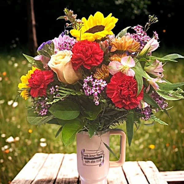 Mixed bouquet in a pink handled tumbler with sunflowers and carnations