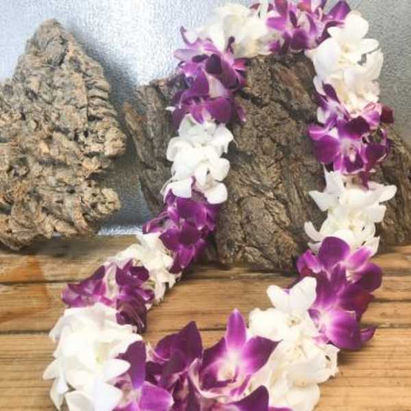 Purple and white orchid lei draped over wood