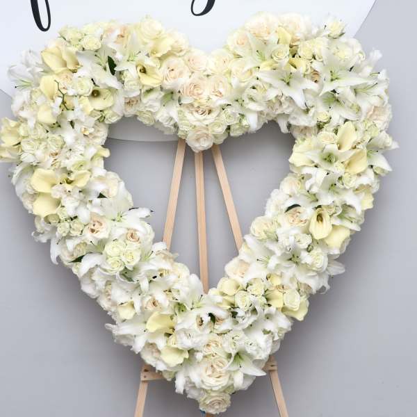 Heart-shaped white floral wreath on a wooden easel