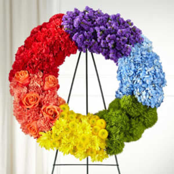 Circular floral wreath in rainbow colors on a black stand