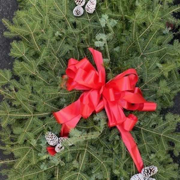 Green holiday wreath with pinecones and a red bow