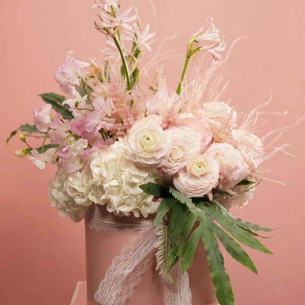 Pastel bouquet of white and blush flowers in a pink hatbox