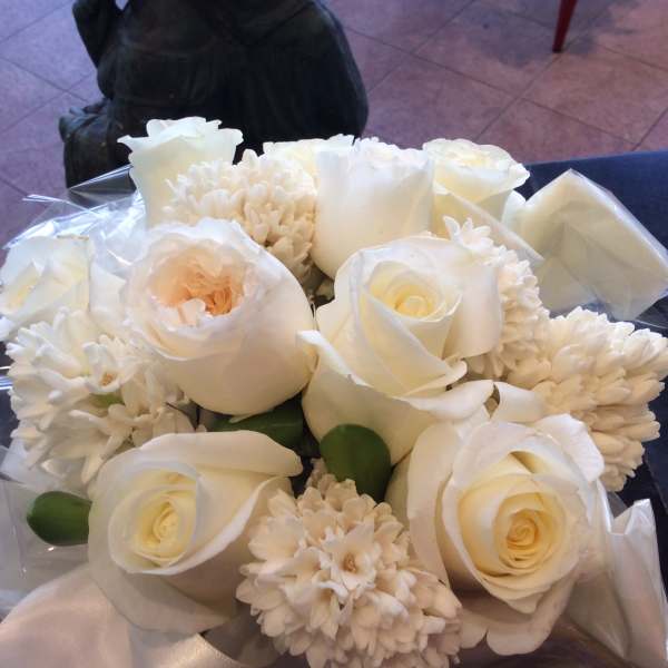 Bouquet of white roses and white chrysanthemums wrapped in clear plastic