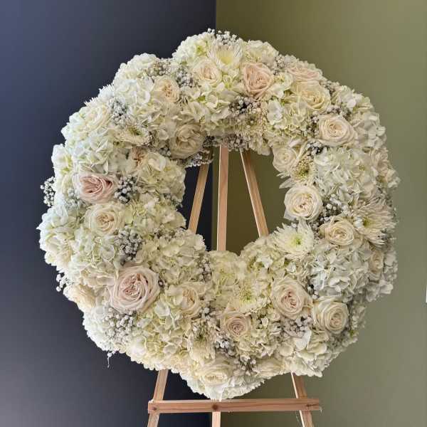 Large white floral wreath on a wooden easel