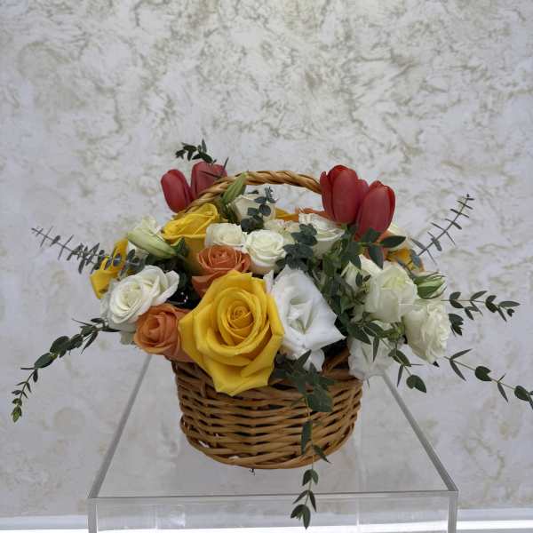Basket of mixed roses with red tulips and greenery