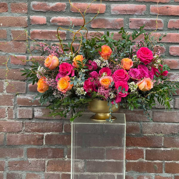 Arrangement of pink and orange roses in a gold vase