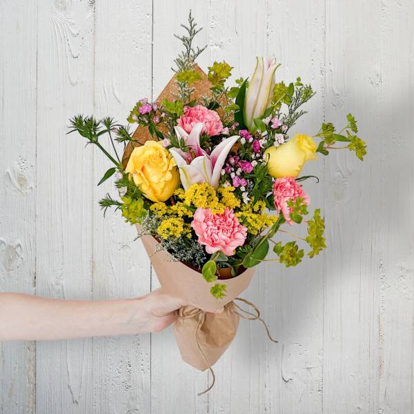 Hand-tied bouquet with yellow roses, pink carnations, and white lilies