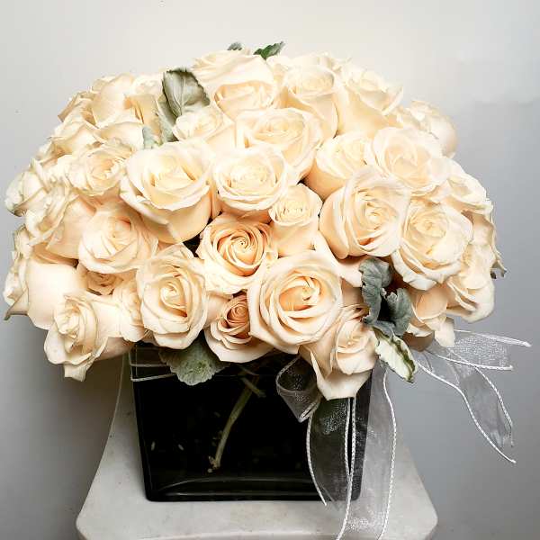 Bouquet of pale peach roses in a black vase with a sheer ribbon