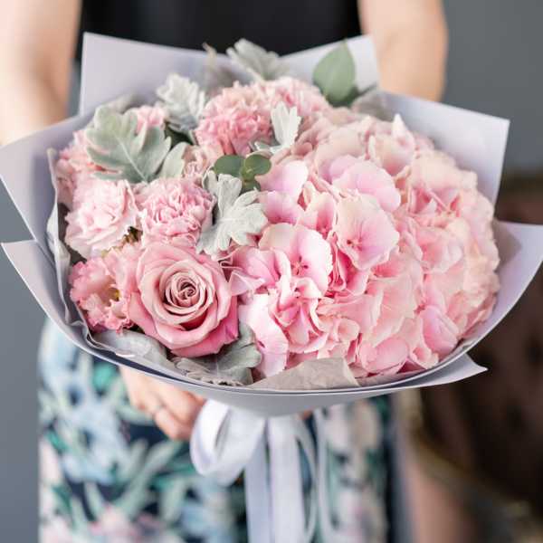 Pink bouquet with roses, carnations, and hydrangea wrapped in lavender paper
