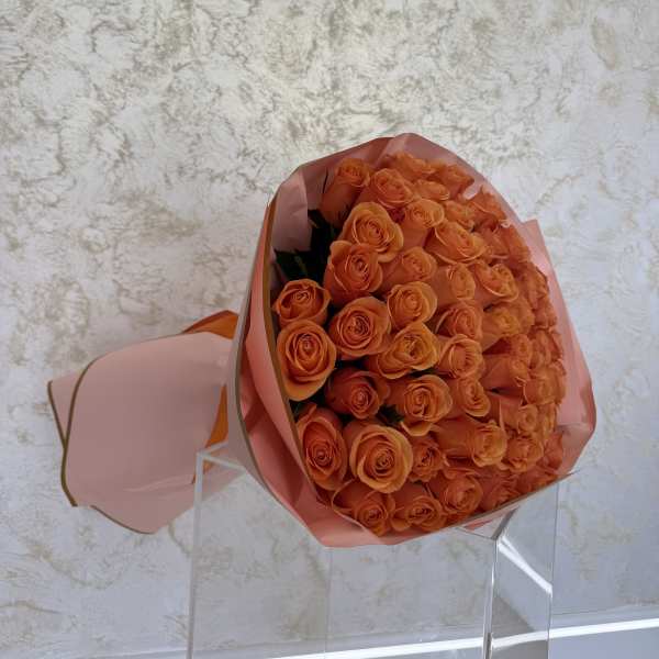Bouquet of orange roses wrapped in pink paper