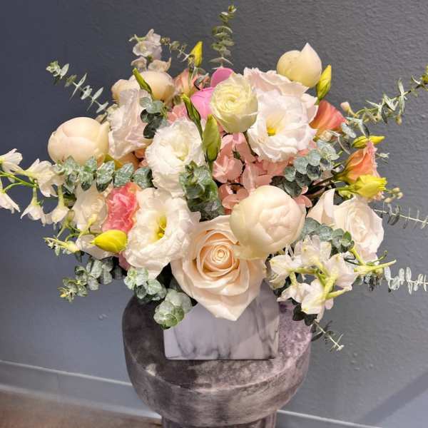 Pastel bouquet of roses, tulips, and white blooms in a marble vase