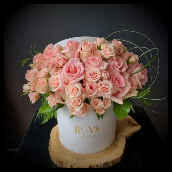Pink rose bouquet in a white hatbox on a wood slice