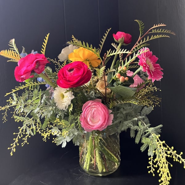 Bright mixed bouquet in a clear glass vase with pink, yellow, and white blooms