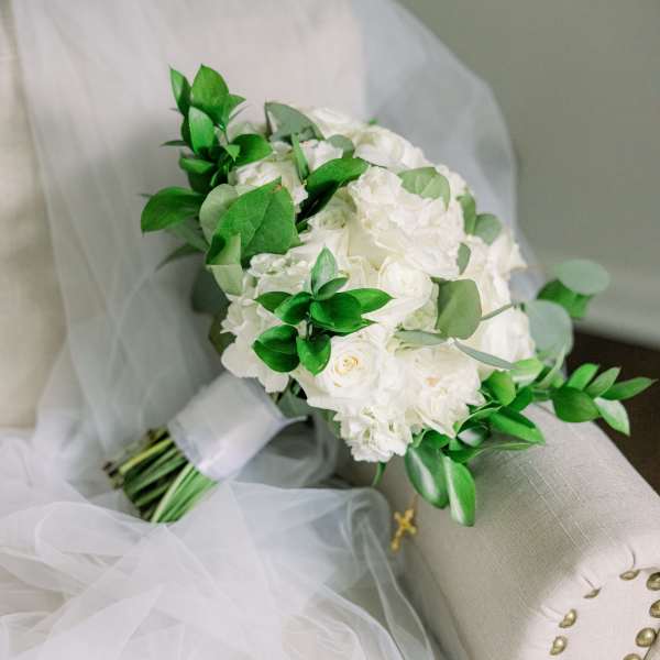 White bridal bouquet with green foliage on a chair