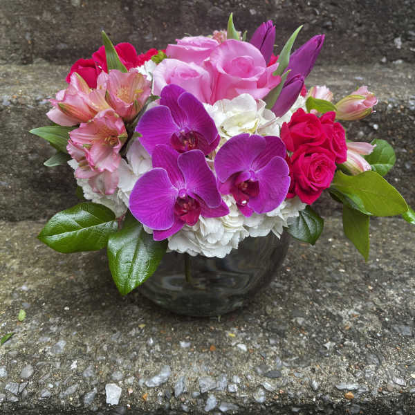 Mixed pink and purple bouquet in a dark glass vase
