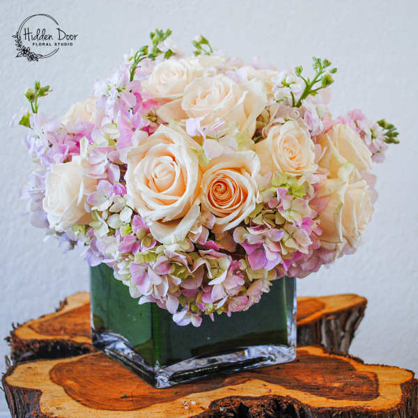 Cream and pink rose bouquet in a square glass vase