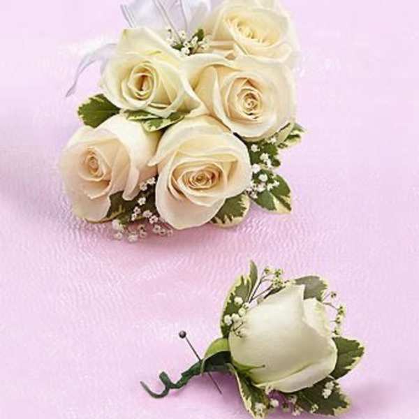 Ivory rose corsage and boutonniere with ribbon on a pink surface