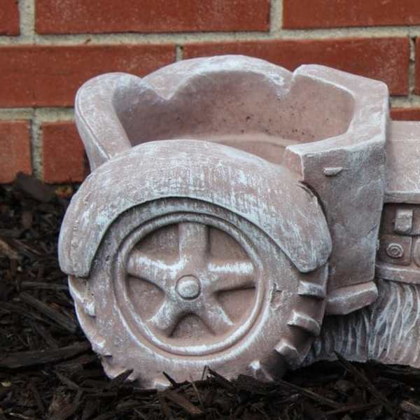 Decorative tractor-shaped planter in a garden bed
