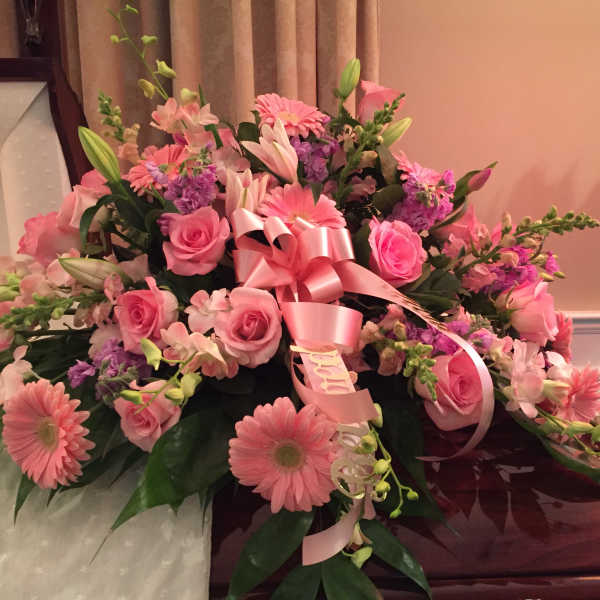 Pink floral casket spray with roses, lilies, and gerbera daisies