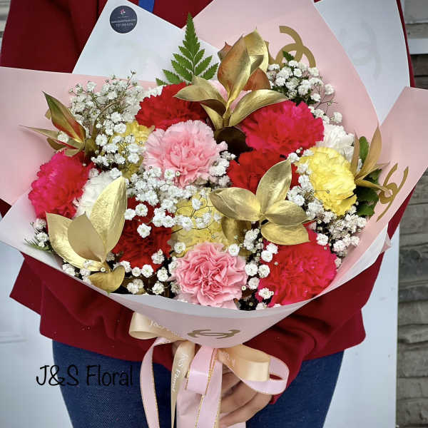 Handheld bouquet of pink, red, yellow, and white carnations with baby's breath
